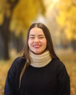 slečna v parku při podzimu, na krku má pletený nákrčník z příze Andes značky DROPS