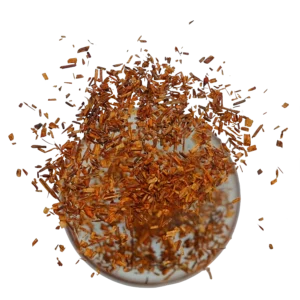 Rooibos neboli čajovec kapský bez kofeinu, který padá do hrnku.