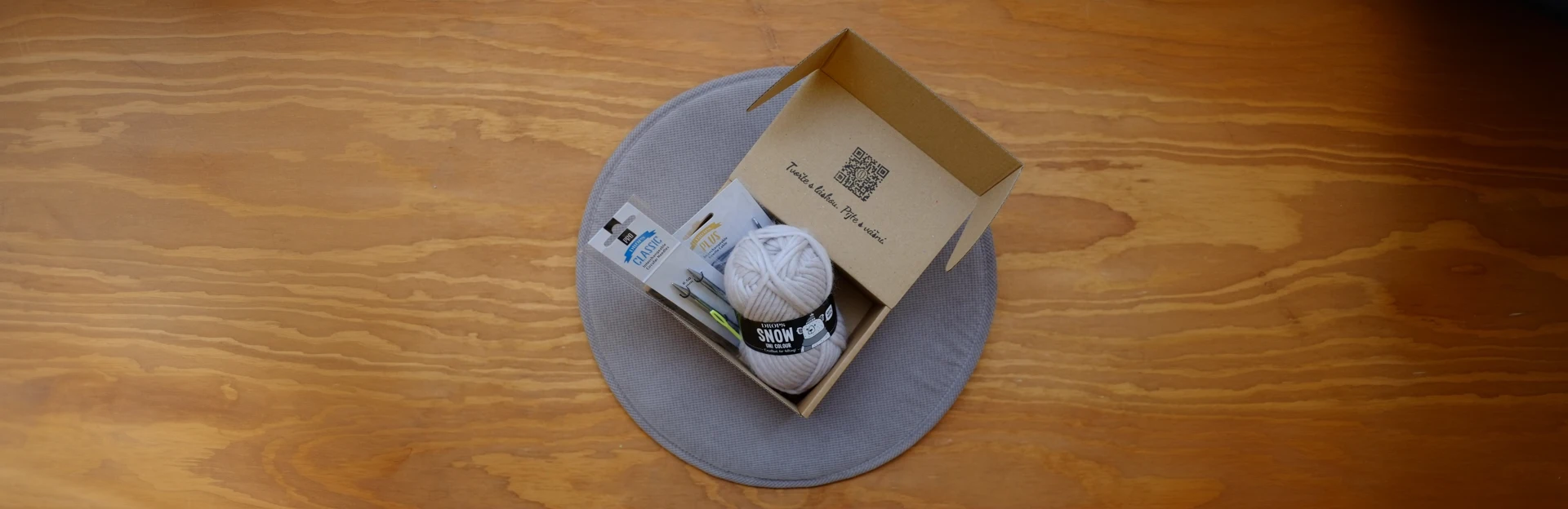 otevřený DIY Box který obsahuje sadu na pletení čelenky na dřevěném stole