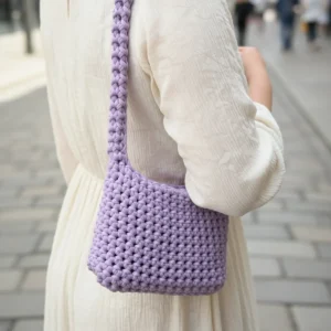 Paní v bílých šatech má přes rameno fialovou háčkovanou kabelku ze šňůry bobilon medium