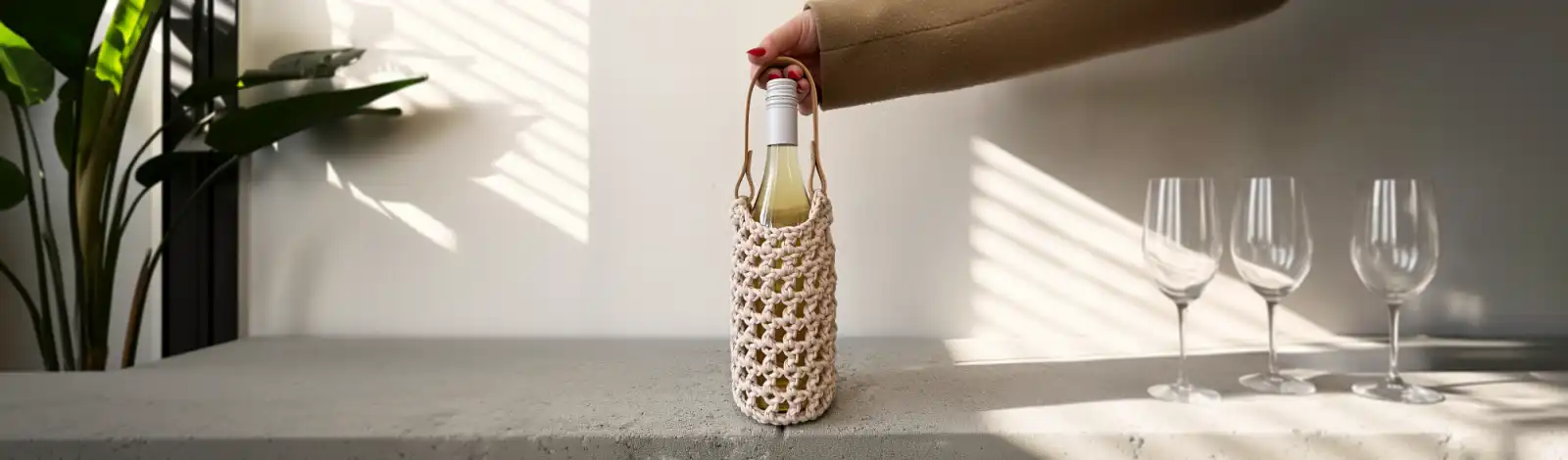 háčkovaný nosič na víno na baru vedle skleniček na víno